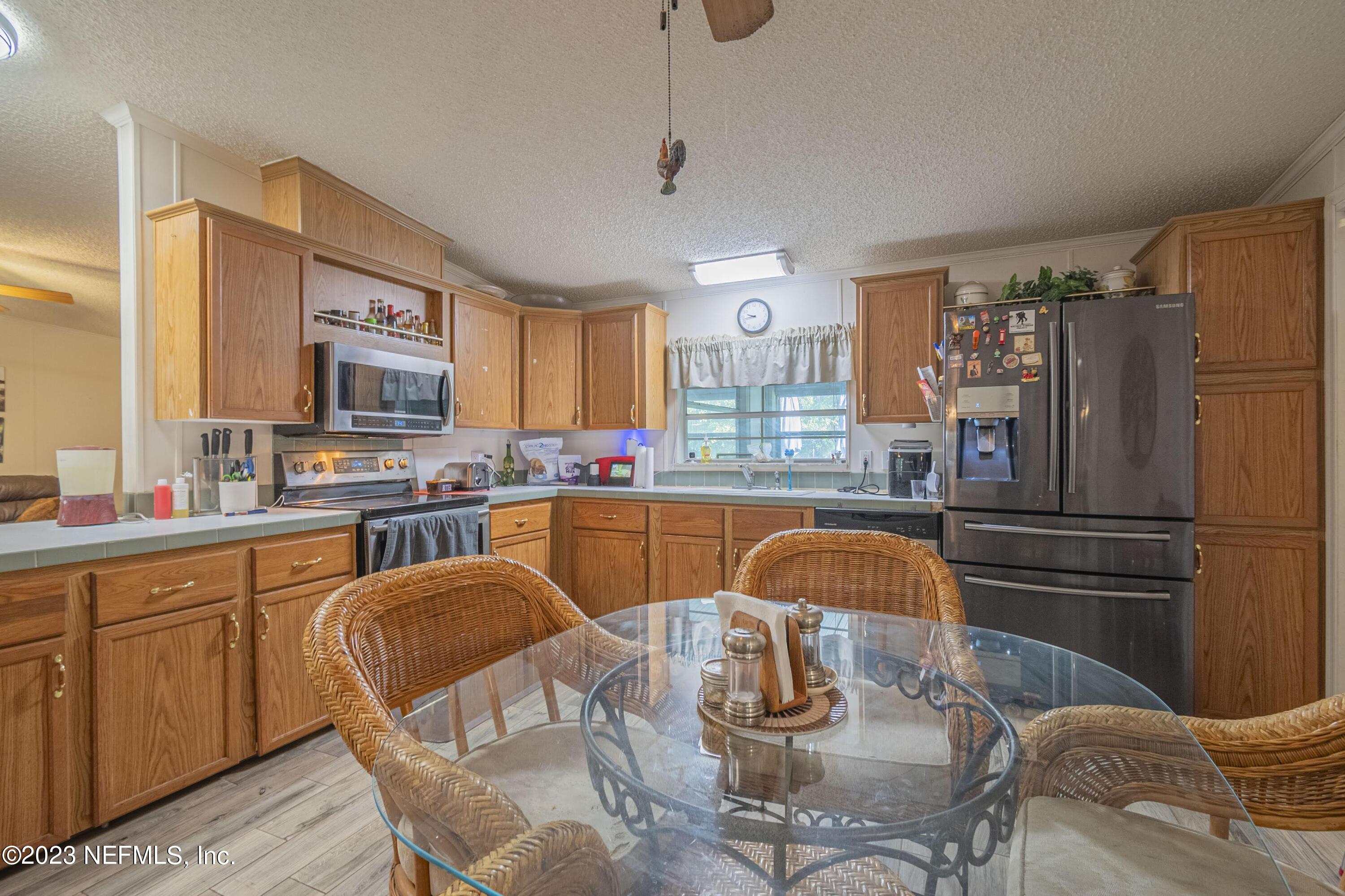 24429 River Road Astor, FL 32102 - Photo 71 of 130 a kitchen with stainless steel appliances granite countertop a refrigerator a stove a sink dishwasher a dining table and chairs with wooden floor