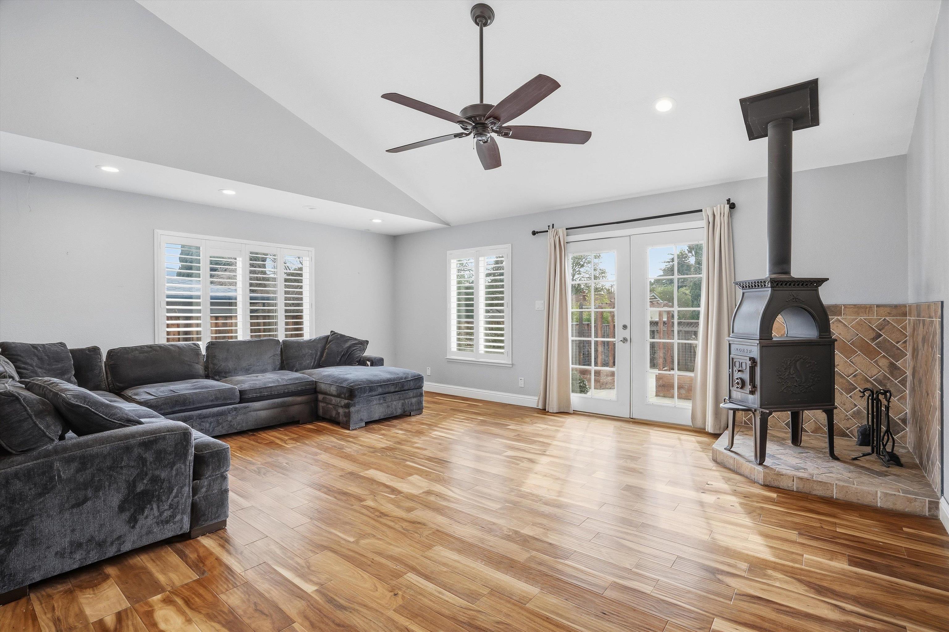 4054 Kimberly Place Concord, CA 94521 - Photo 13 of 16 Living room area featuring French doors to rear yard, ceiling fan, light wood-style flooring, lofted ceiling, and a wood stove