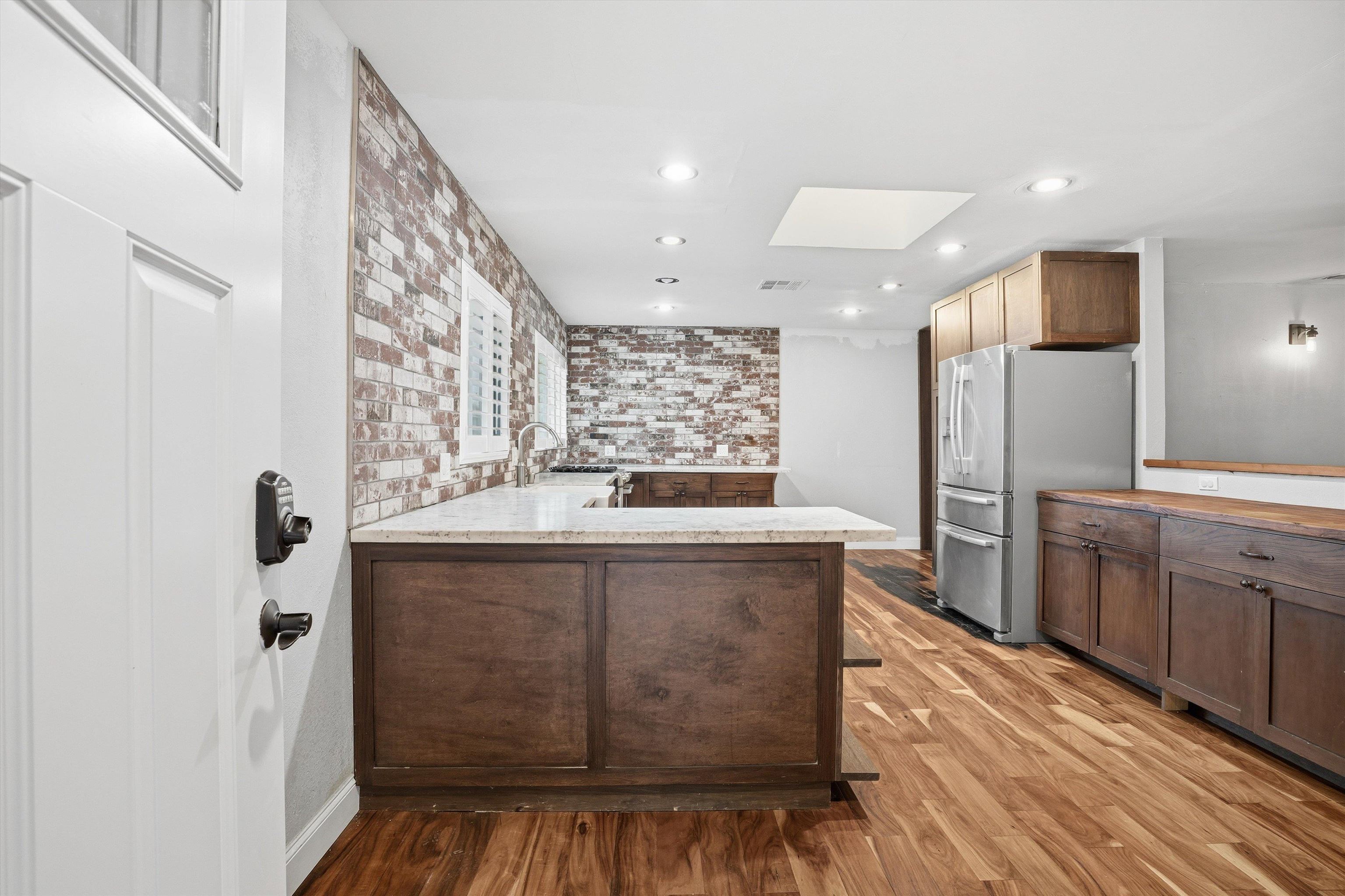 4054 Kimberly Place Concord, CA 94521 - Photo 3 of 16 Kitchen with a peninsula, stainless steel refrigerator with ice dispenser, a skylight, dark wood finish cabinets, and light wood-style floors