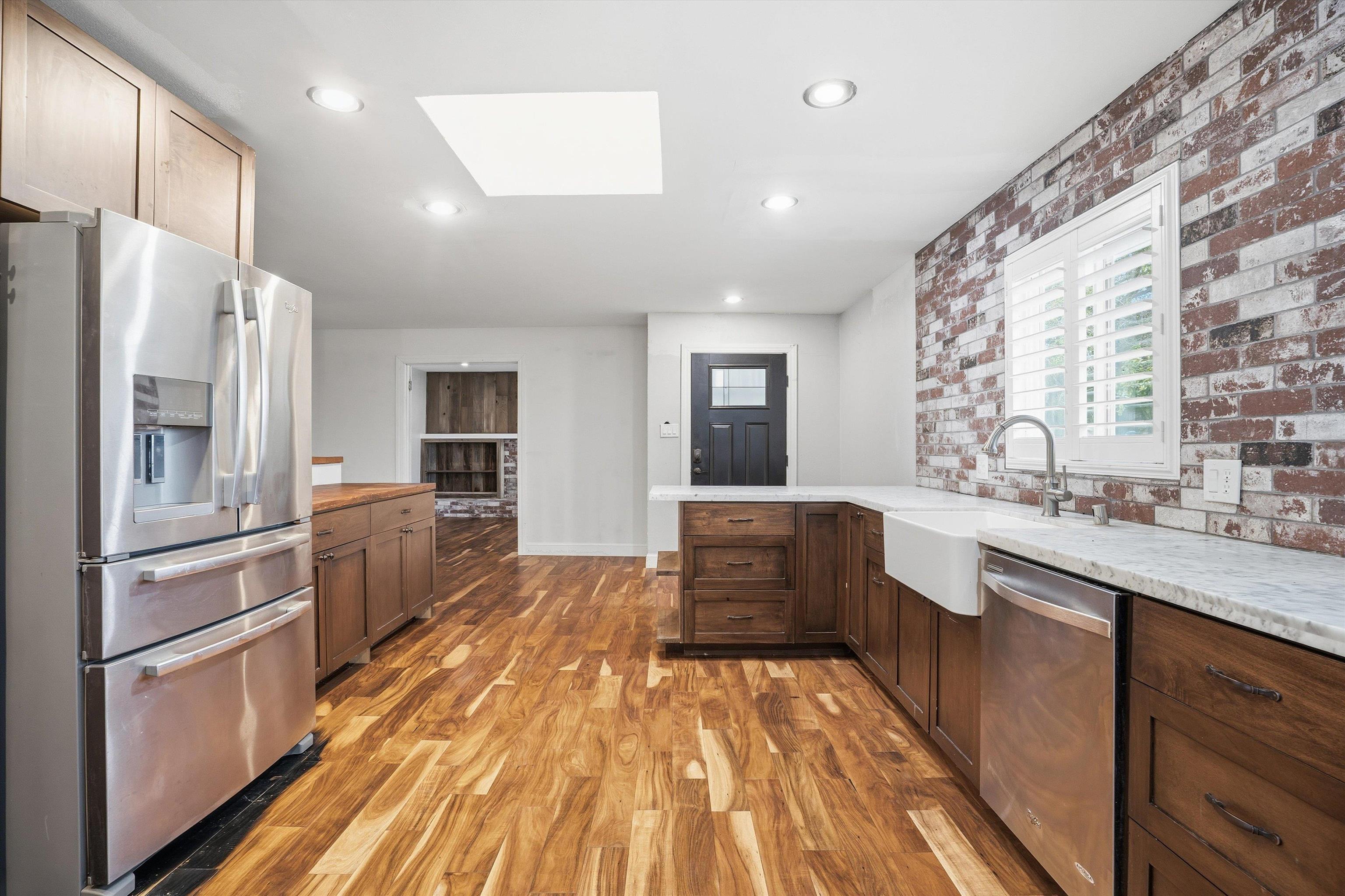 4054 Kimberly Place Concord, CA 94521 - Photo 6 of 16 Kitchen featuring a peninsula, stainless steel appliances, a skylight, light wood-style floors, and brick wall