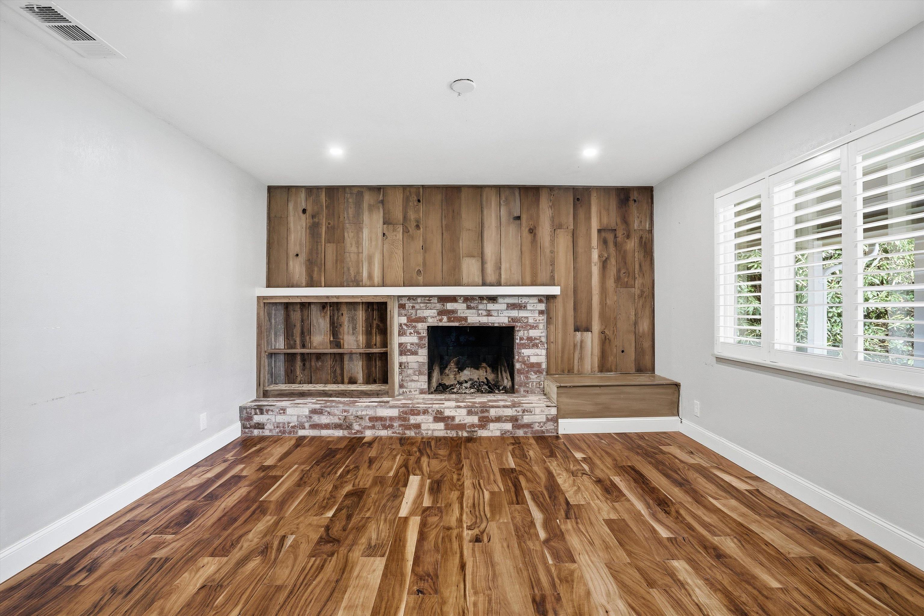 4054 Kimberly Place Concord, CA 94521 - Photo 8 of 16 Parlor bonus room with wooden walls, wood finished floors, a brick fireplace, an accent wall, and recessed lighting