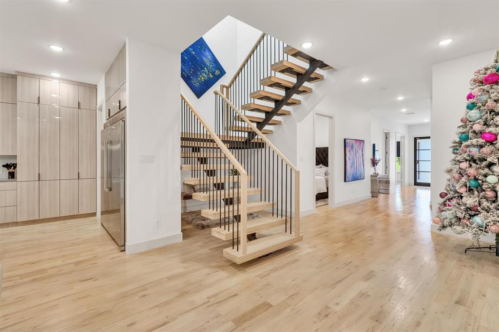 7519 Robin Road Dallas, TX 75209 - Photo 6 of 33 Floating staircase with metal balusters, light wood-finish flooring, recessed lighting, integrated refrigerator, and light wood-finish cabinetry