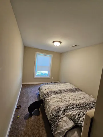 a bed sitting in a spacious bedroom next to a window