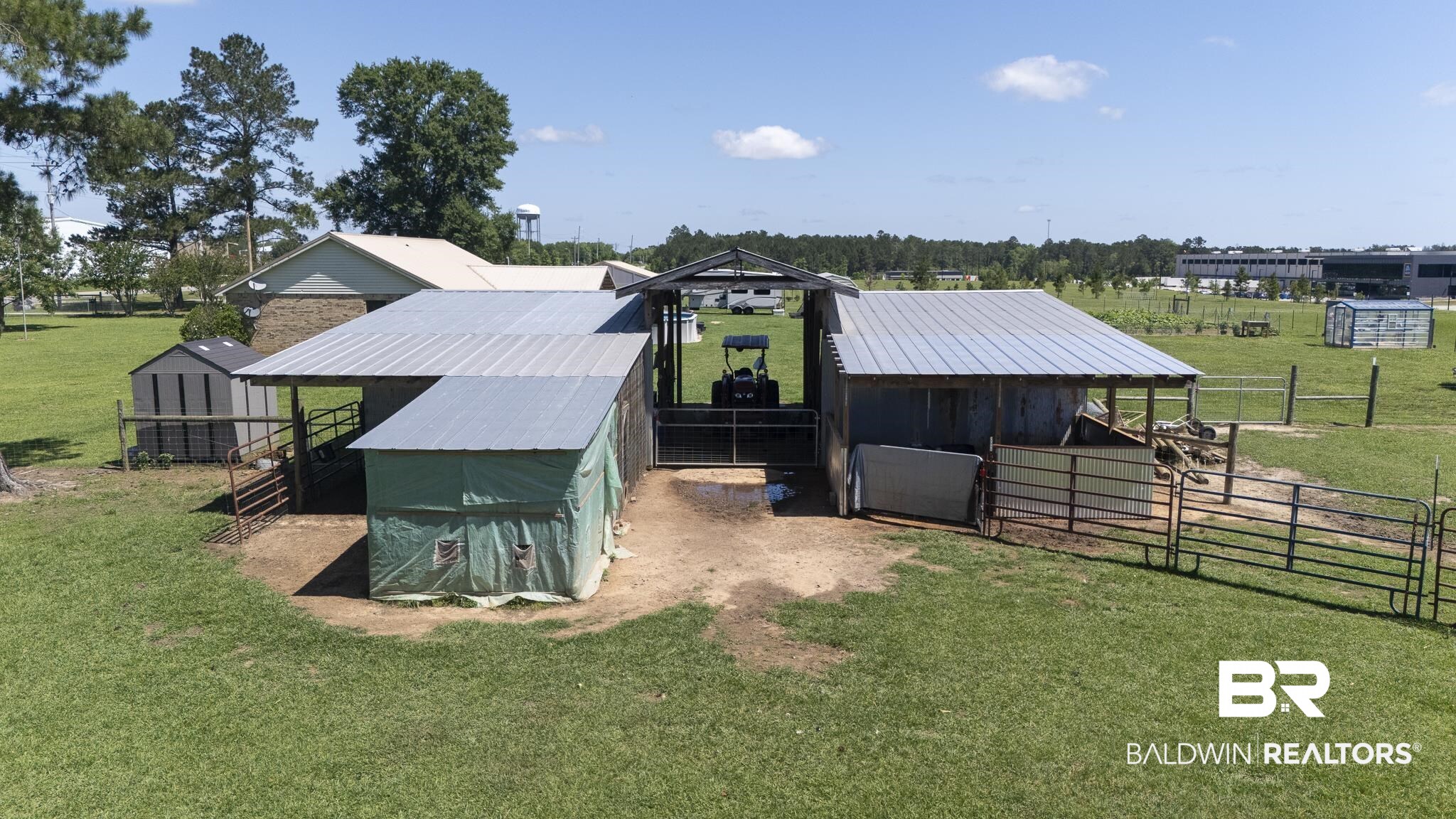 30580 County Road 49 Loxley, AL 36551 - Photo 26 of 32 Barn structure with metal roofing, multiple fenced enclosures, and a dirt ground surface