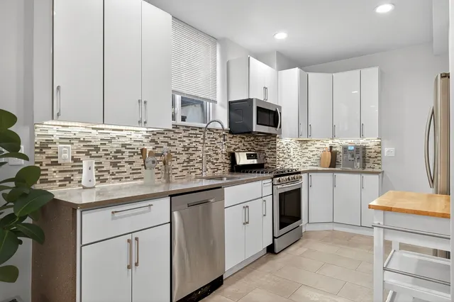 a kitchen with kitchen island granite countertop a sink stainless steel appliances and cabinets