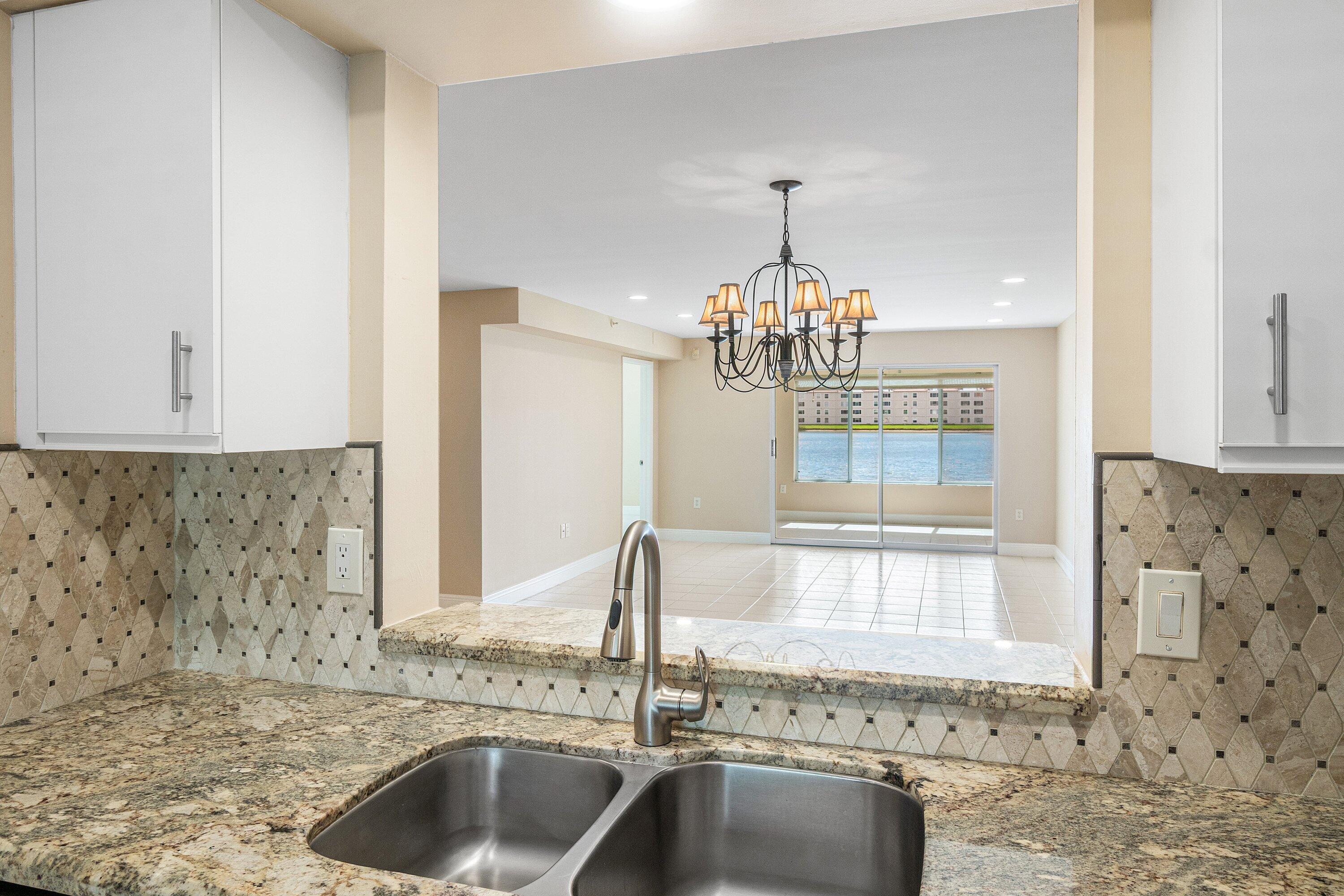14096 Huntington Pointe Drive, Unit 106 Delray Beach, FL 33484 - Photo 19 of 47 a kitchen with granite countertop a sink and a window