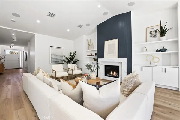 a large room with stainless steel appliances kitchen island granite countertop a dining table chairs and a wooden floors