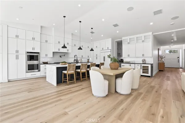 a large kitchen with stainless steel appliances kitchen island granite countertop a table chairs sink and cabinets