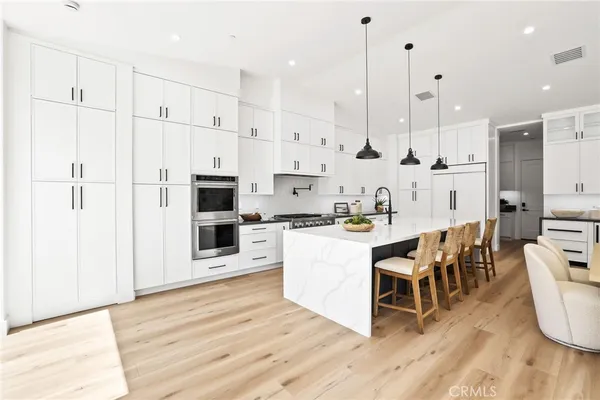 a kitchen with stainless steel appliances a stove a sink a refrigerator and chairs