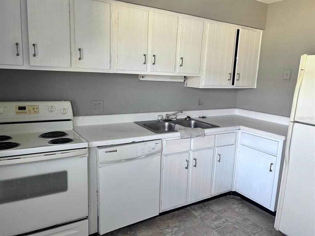 1625 West Oak Ridge Road, Unit C Orlando, FL 32809 - Photo 6 of 11 a kitchen with white cabinets and white appliances