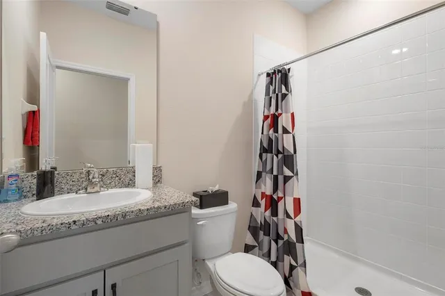 a bathroom with a granite countertop sink a toilet and shower