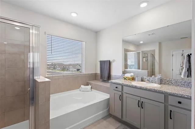 a bathroom with a sink double vanity granite tub shower and a mirror