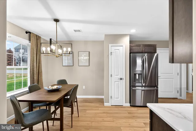 a kitchen with stainless steel appliances a dining table chairs and refrigerator