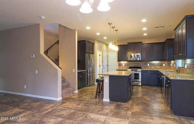 a kitchen with stainless steel appliances kitchen island granite countertop a refrigerator and a stove top oven