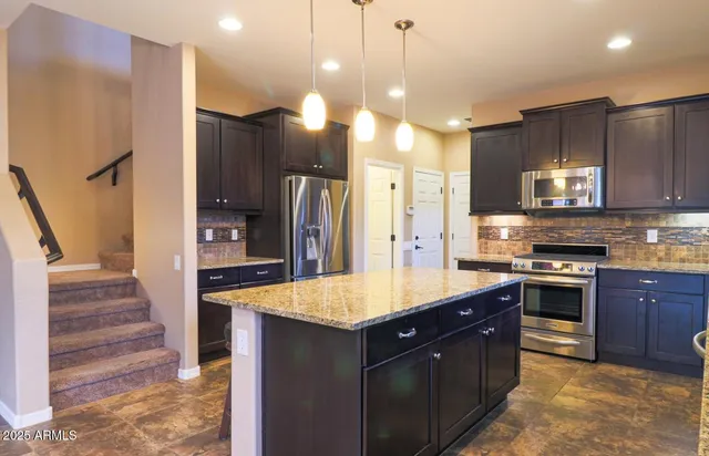 a large kitchen with stainless steel appliances a stove a sink and a refrigerator