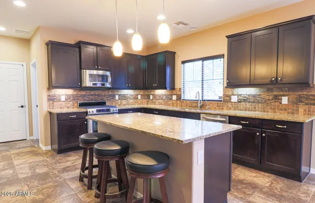 a kitchen with kitchen island granite countertop wooden cabinets and a refrigerator