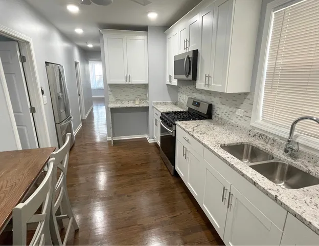 a kitchen with granite countertop a sink a counter top space stainless steel appliances and cabinets