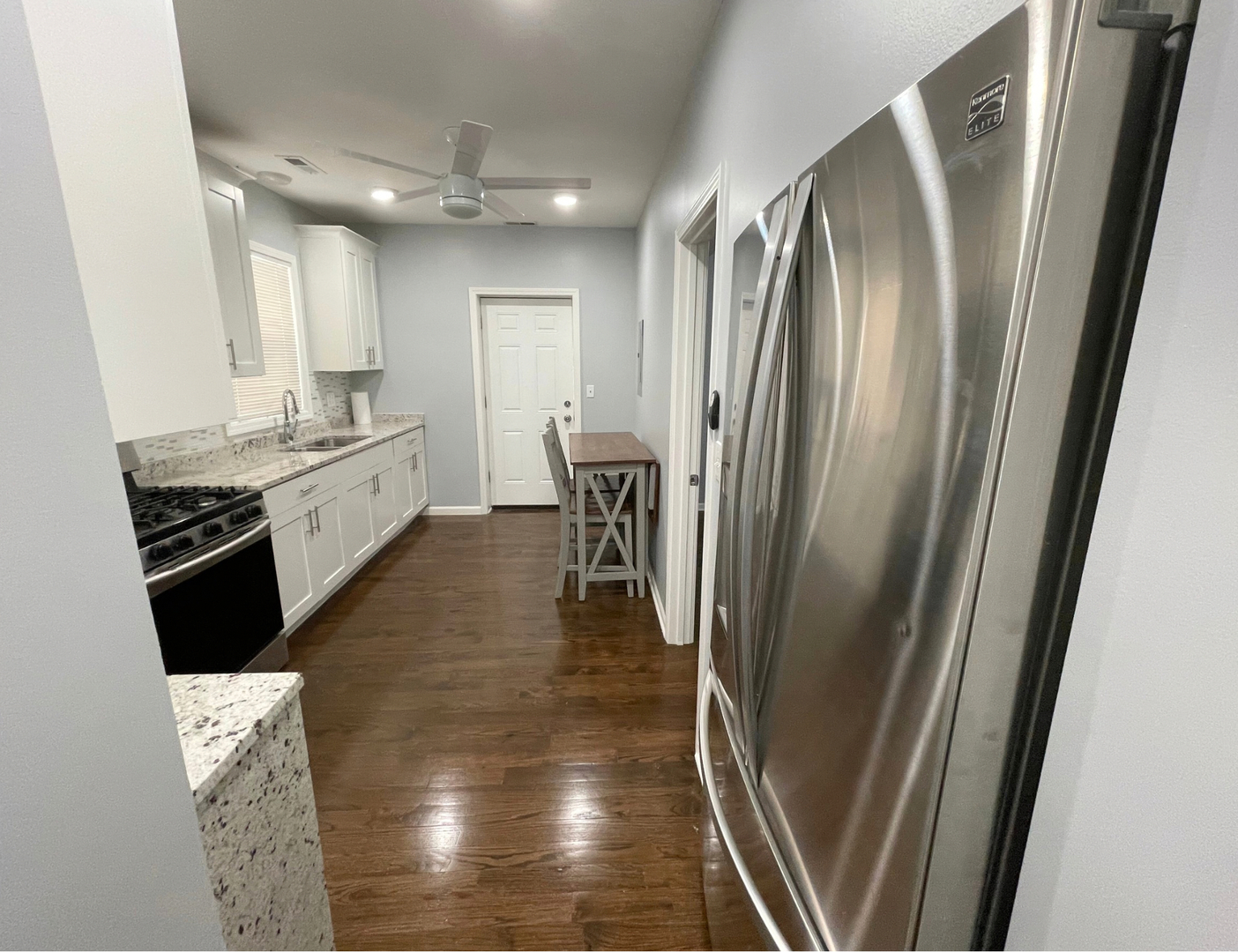 1836 South May Street, Unit 1 Chicago, IL 60608 - Photo 4 of 15 a kitchen with granite countertop a refrigerator a stove a sink and white cabinets