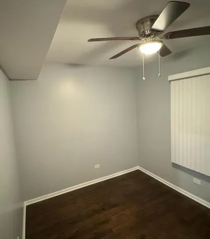 an empty room with wooden floor and fan