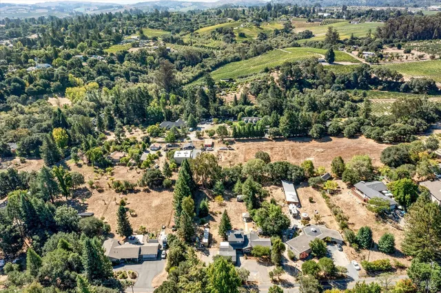an aerial view of residential houses with outdoor space and trees