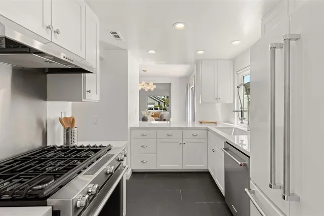 a kitchen with stainless steel appliances a sink dishwasher a stove and white cabinets