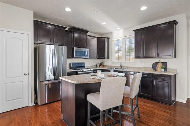a kitchen with stainless steel appliances granite countertop a refrigerator a sink a stove a dining table and chairs