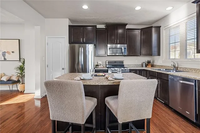 a kitchen with stainless steel appliances granite countertop a dining table chairs microwave and sink