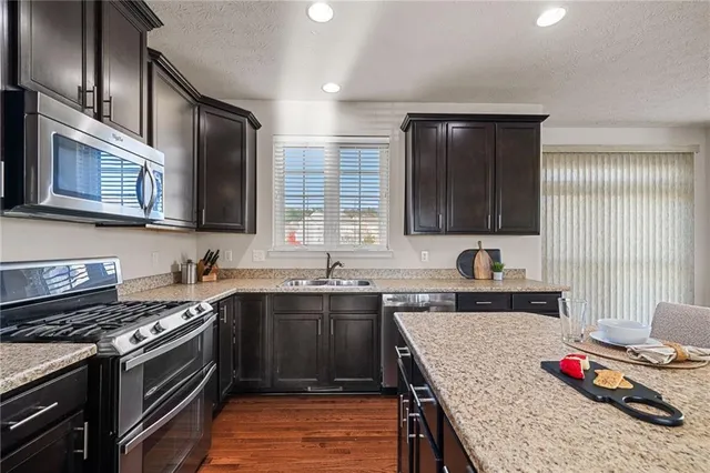a kitchen with stainless steel appliances granite countertop a sink stove and cabinets