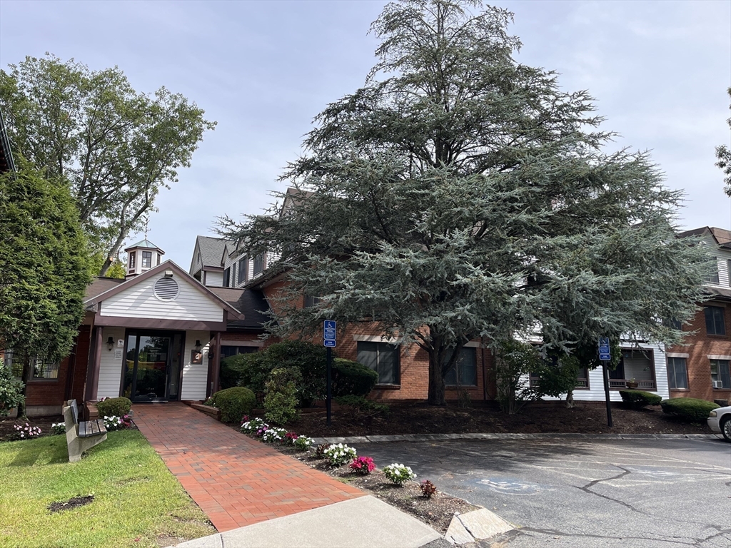 324 Washington Street, Unit 103 Wellesley, MA 02481 - Photo 11 of 13 a front view of a house with a garden and sitting area