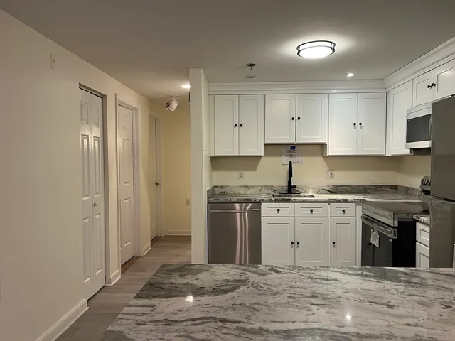 a kitchen with stainless steel appliances granite countertop a stove top oven a sink and a refrigerator