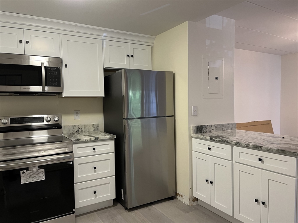 324 Washington Street, Unit 103 Wellesley, MA 02481 - Photo 13 of 13 a kitchen with granite countertop cabinets and steel stainless steel appliances