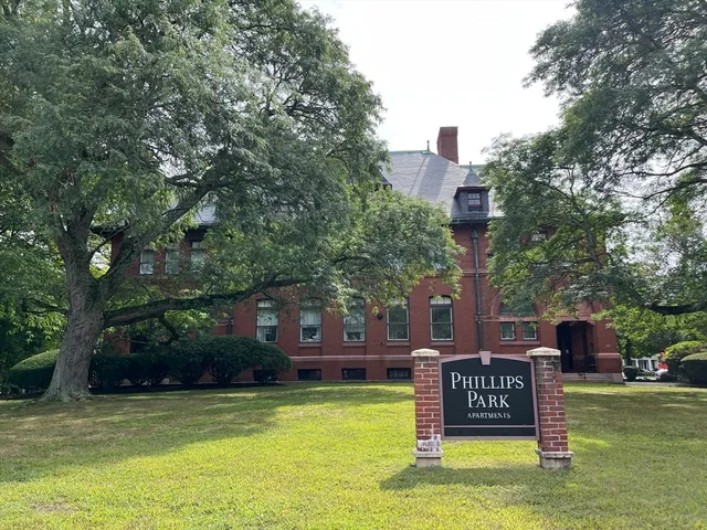 a sign board with a bench and trees