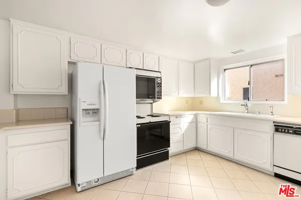 a kitchen with white cabinets and refrigerator