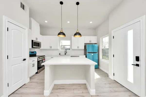 a large kitchen with stainless steel appliances kitchen island granite countertop a sink and a refrigerator
