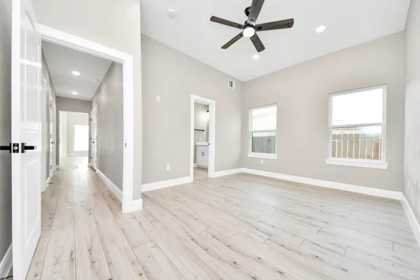 a view of empty room with wooden floor and fan
