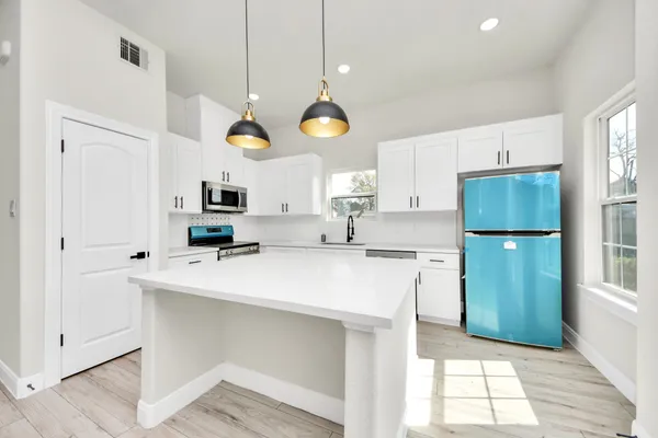 a kitchen with stainless steel appliances a stove a refrigerator a sink cabinets and a window