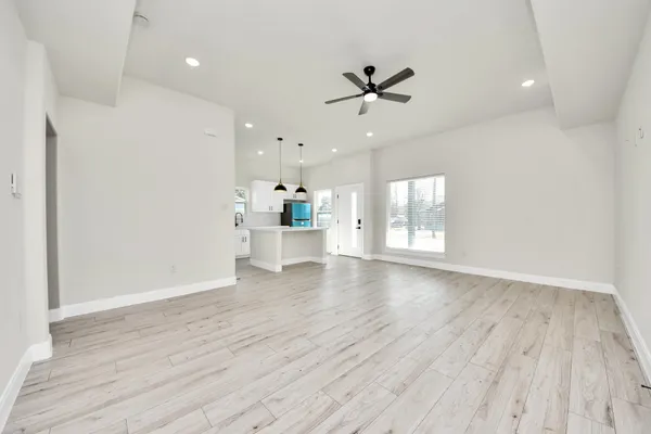 a view of an empty room with a window and wooden floor