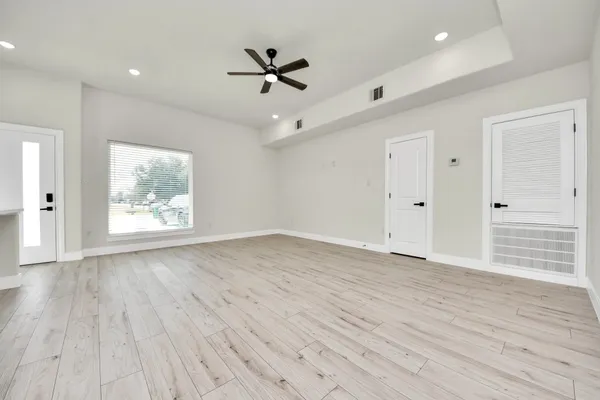 a view of an empty room with a window and wooden floor