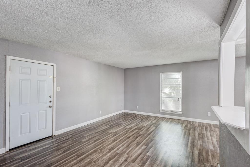 5063 Ridglea Lane, Unit 1002 Fort Worth, TX 76116 - Photo 2 of 11 an empty room with wooden floor and windows