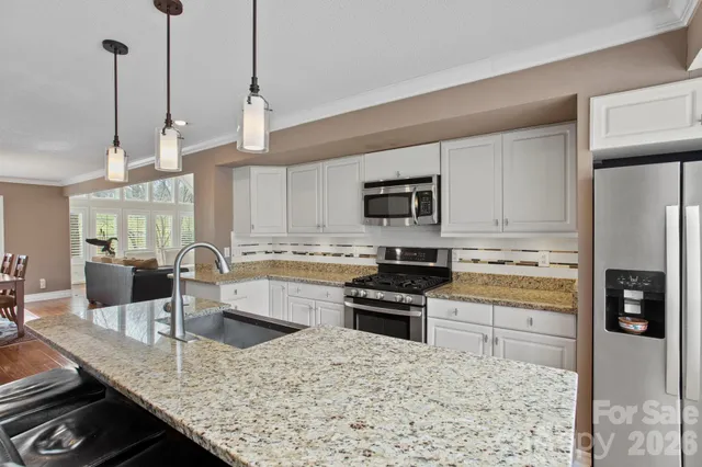 a kitchen with stainless steel appliances kitchen island granite countertop a sink stove and refrigerator