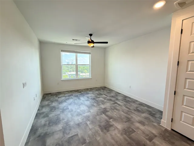 an empty room with windows and ceiling fan