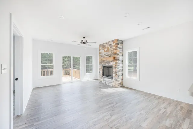 a view of a livingroom with a fireplace a ceiling fan and wooden floor