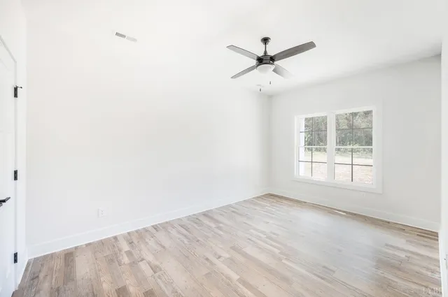 an empty room with wooden floor and ceiling fan