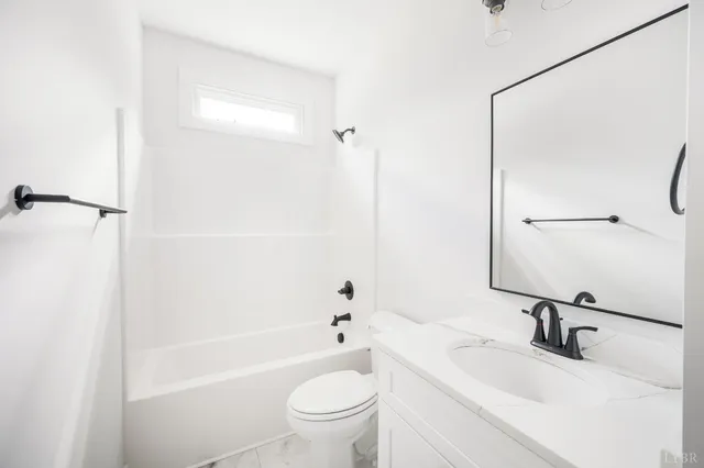 an empty room with wooden floor a ceiling fan and windows