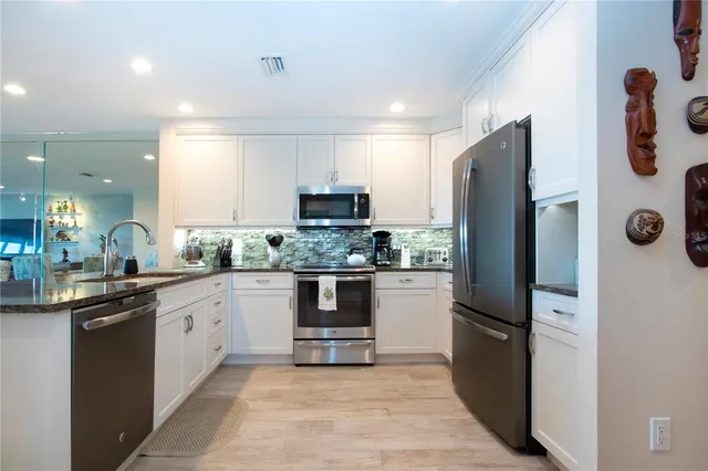 a kitchen with stainless steel appliances granite countertop white cabinets and black stove top oven with granite countertops