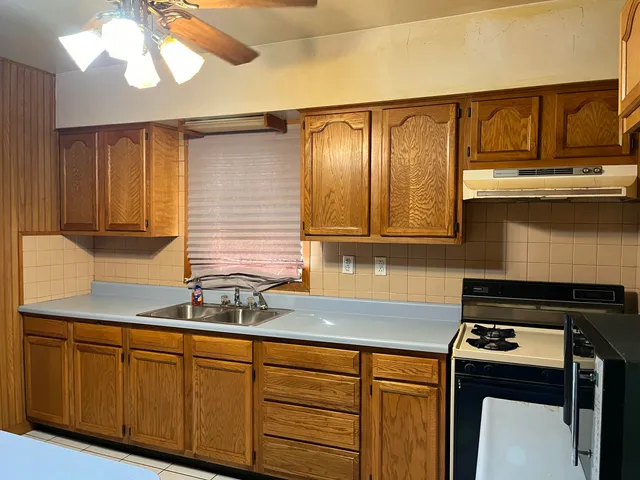 a kitchen with granite countertop a sink a stove and cabinets