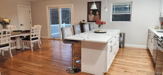 a dining hall with stainless steel appliances kitchen island granite countertop wooden floor a dining table and chairs