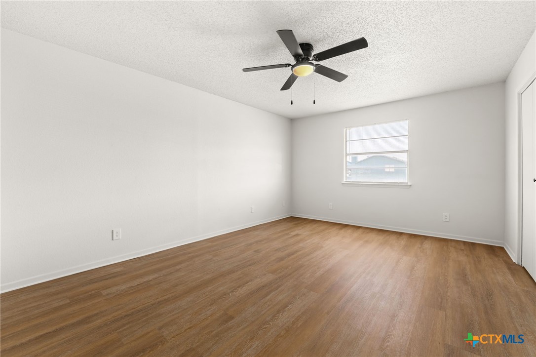 1005 Eastside Drive, Unit D Killeen, TX 76543 - Photo 6 of 9 an empty room with wooden floor fan and windows