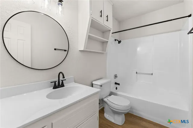 an empty room with wooden floor ceiling fan and windows