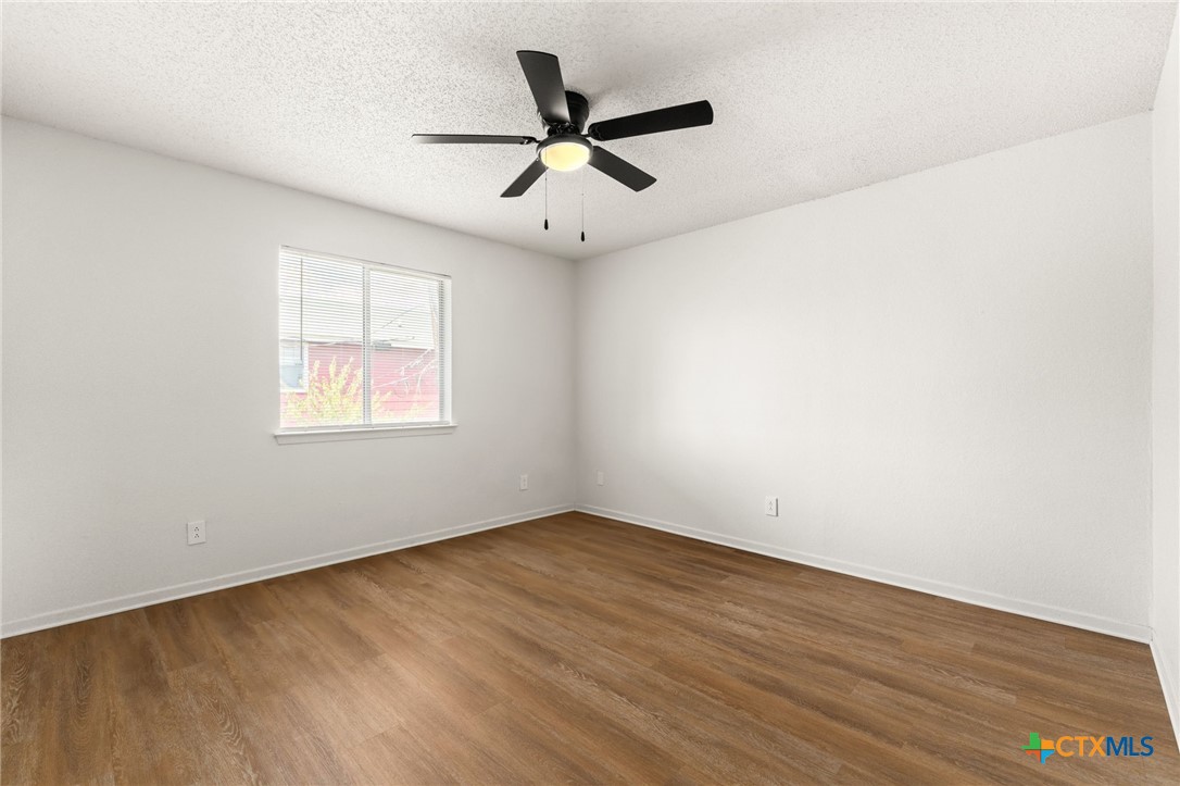 1005 Eastside Drive, Unit D Killeen, TX 76543 - Photo 9 of 9 an empty room with wooden floor ceiling fan and windows